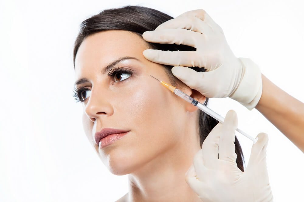 A woman getting her face waxed by an esthetician.