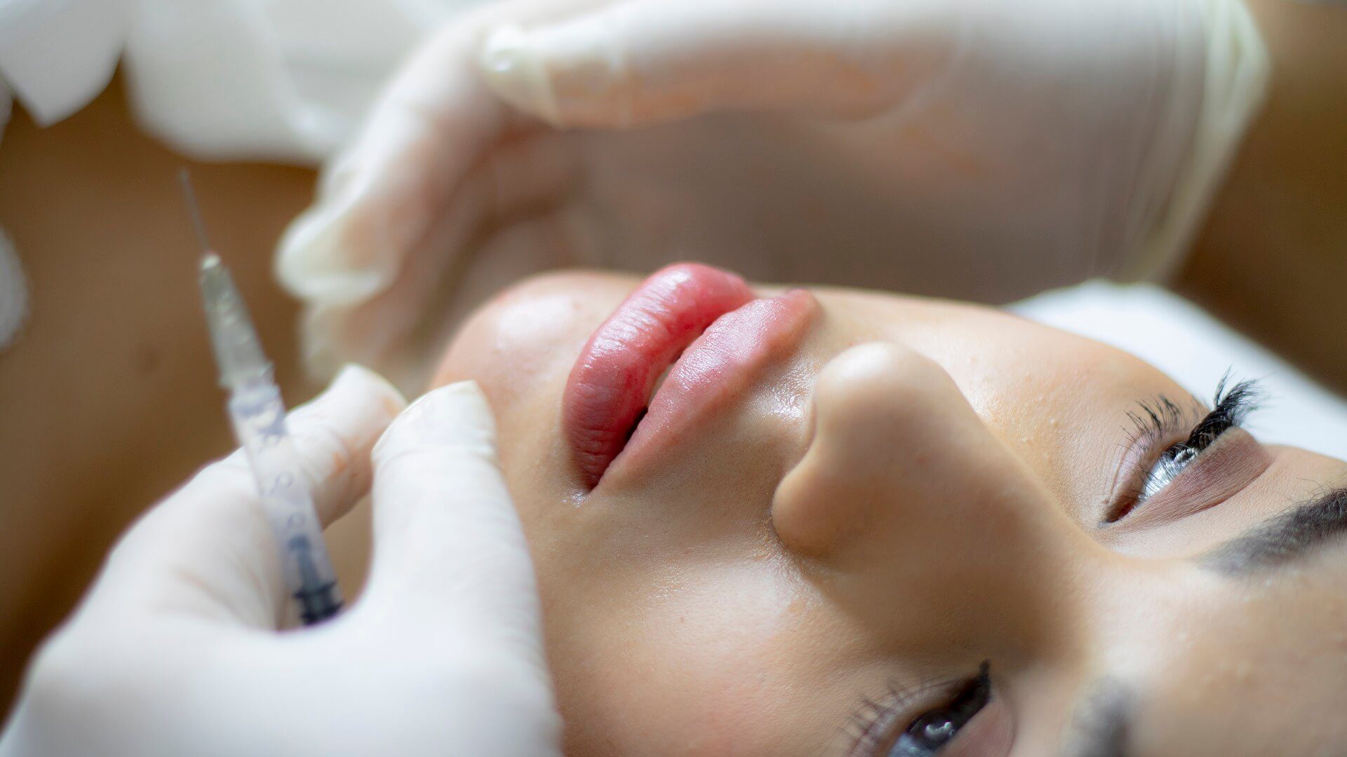 Close up of beautician expert's hands injecting in female lips