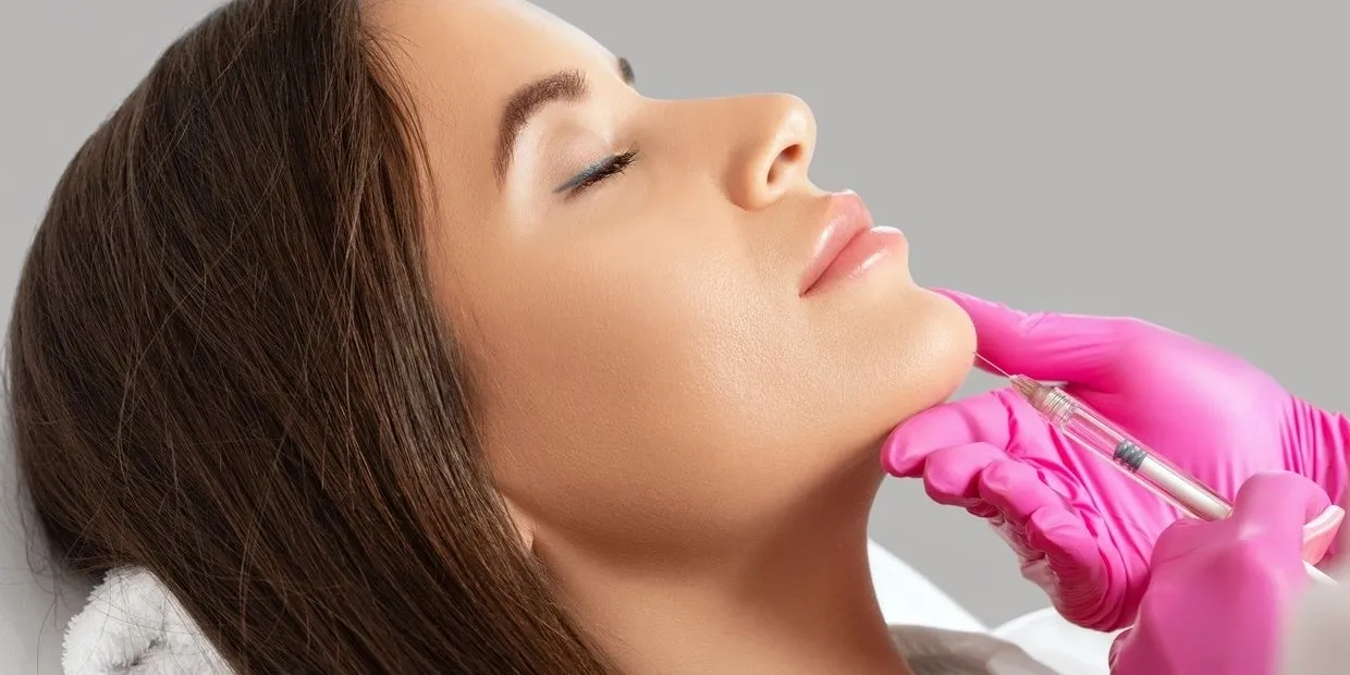 A woman is getting her chin examined by an esthetician.