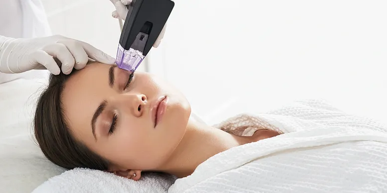 A woman getting her face cleaned with an electric device.