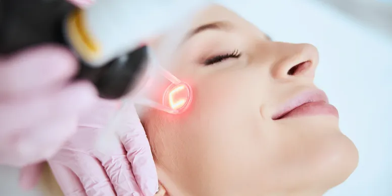 A woman getting her face cleaned with an electric device.