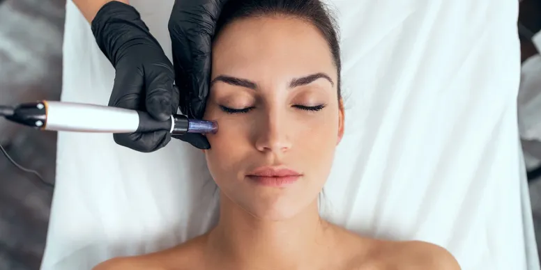 A woman getting her eyes cleaned by an esthetician.