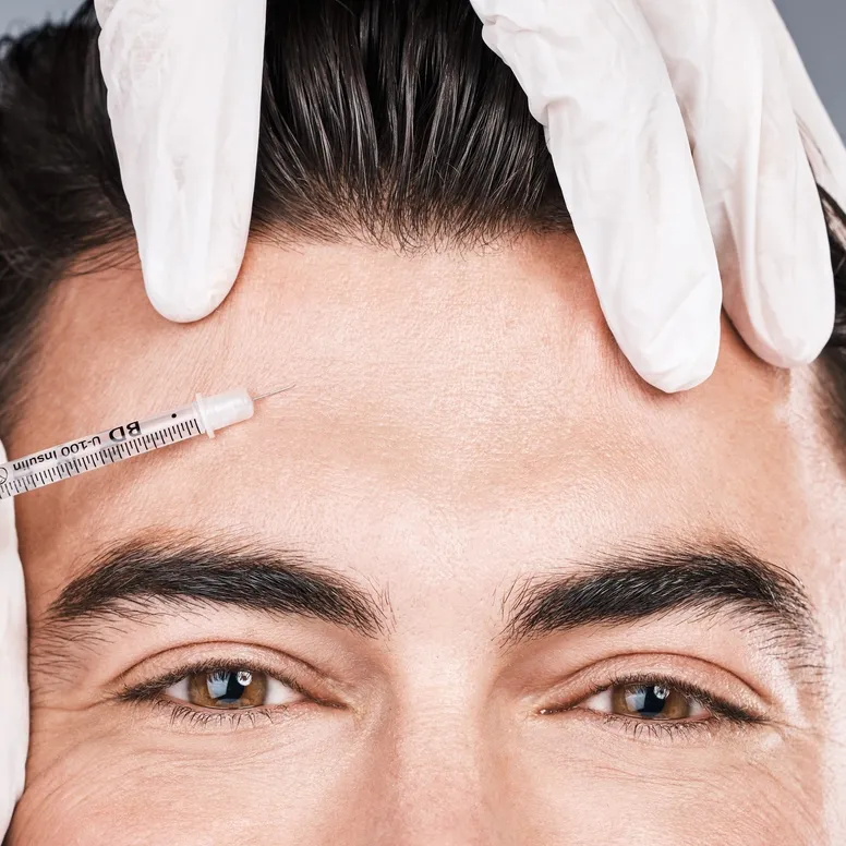 Man's forehead and cosmetologist's hands making anti-wrinkles injections