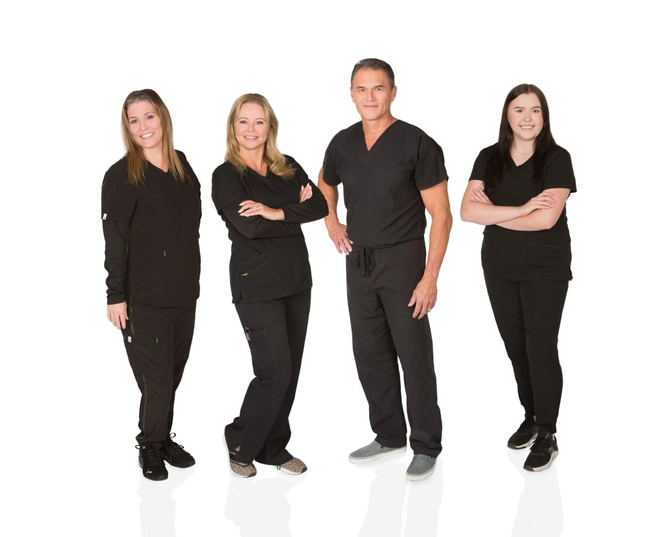 Four people in black scrubs standing together on a white background